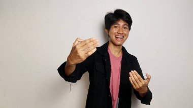 Asyalı yakışıklı, soyutlanmış beyaz arka planda genç bir adam davet ediyor. Gelmene sevindim.