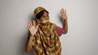 Endonezyalı hırsız sarong bir yüz örtüsü takıyordu ve beyaz arka planda tanınmıyordu.