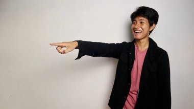 Havalı kot gömlek giyen heyecanlı genç Asyalı adam izole edilmiş beyaz arka planda yan pozlar veriyor.