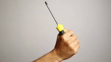 İzole edilmiş beyaz bir arka planda tornavida tutan bir adam.