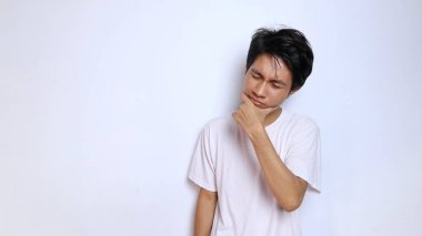 Beyaz gömlekli genç Asyalı adam ciddi bir ifadeyle izole edilmiş beyaz bir arka plan düşünüyor.