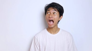 Beyaz gömlekli, komik, şok edici jestli genç Asyalı adam izole edilmiş beyaz arka plana bakıyor.