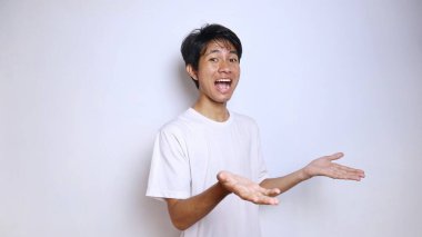 Heyecanlı, beyaz gömlekli, kolları açık, beyaz arka planlı Asyalı genç bir adam.