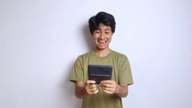 Genç Asyalı adam ifadesi, hesap makinesini tutan hareketli hareketler, izole edilmiş beyaz arka grond.