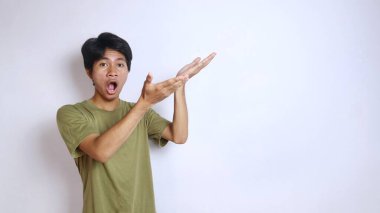 Asyalı genç bir adam, izole edilmiş beyaz bir arkaplan ile boş bir tarafı işaret ediyor. Boşluğu kopyala