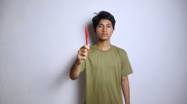 Genç Asyalı adam beyaz arka planda kalem tutuyor.