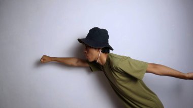 Genç Asyalı adam, izole edilmiş beyaz bir arka planda uçmak gibi komik hareketler yapıyor.