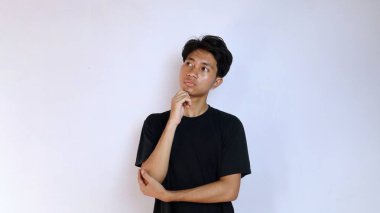 Siyah tişörtlü genç Asyalı adam izole edilmiş beyaz arka planda bir şey düşünüyor. Boşluğu kopyala