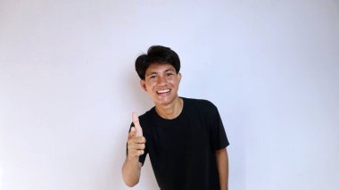 Siyah tişörtlü heyecanlı genç Asyalı adam izole edilmiş beyaz arka planı işaret ediyor. kopyalama alanı, başarı, mutluluk, evet de, tamam, güzel, lezzetli