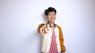 Sıradan gülümseyen, yakışıklı, ceketli Asyalı bir adam izole edilmiş beyaz arka planda bir işaret veriyor.