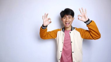 casual happy young handsome asian man wearing jacket gesture okay isolated white background clipart