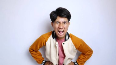 İzole edilmiş beyaz bir arka planda kızgın bir ifadeye sahip ceketli sıradan yakışıklı bir Asyalı.