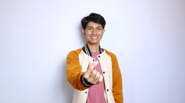 Sıradan gülümseyen, yakışıklı Asyalı bir adam ceketini giyip izole edilmiş beyaz arka planda aşk sembolü veriyor.