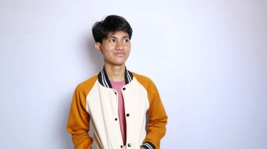 Sıradan gülümseyen genç yakışıklı Asyalı adam izole edilmiş beyaz bir arka planda yan tarafa bakıyor.