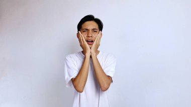 Asyalı genç adam beyaz gömlekli diş ağrısı çekiyor. El hareketi, yanak hareketi, izole beyaz arka plan, kopyalama alanı.