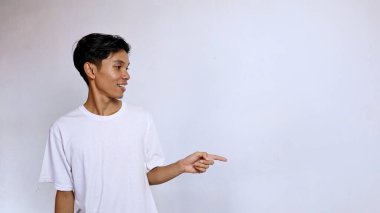 Asian young man smiling wearing white shirt gesturing hand pointing right side and looking right side isolated on white background clipart