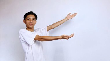 happy young asian man posing showing copy space on the side with both hands on isolated white background clipart