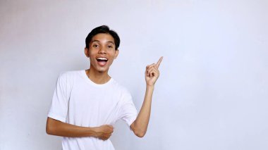 Asian young man happy wearing white shirt hand gesture pointing right side and looking forward with isolated white background clipart