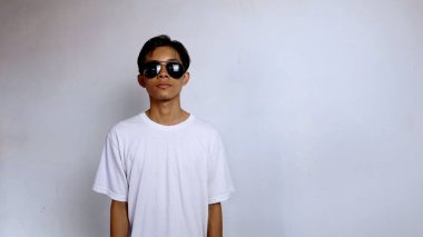 Beyaz gömlek ve güneş gözlüğü takan Asyalı erkek düz yüz ifadesi izole edilmiş beyaz arka plan
