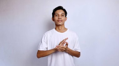 Beyaz tişörtlü genç Asyalı adam izole beyaz arka planda el çırpıyor.