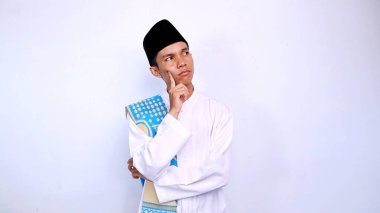 Asyalı genç Müslüman adam ciddi bir ifade bir şey hakkında düşünerek ve yalıtılmış beyaz arka planda yan bakıyor