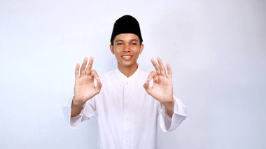 Asyalı Müslüman gençlik gülümsemesi iki elini de izole edilmiş beyaz arka planda kullanarak sembol gösteriyor