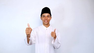 Asyalı Müslüman gençlik gülümsemesi iki elini de izole beyaz arka planda kullanarak baş parmak işareti gösteriyor.