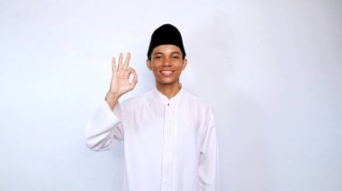 Asyalı Müslüman gençlik gülümsemesi izole beyaz arka planda iyi bir sembol gösteriyor