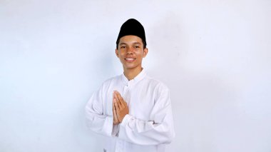 Genç Asyalı müslüman gülümseyen yüz ifadesi izole edilmiş beyaz arkaplan ile selamlama hareketi. İslam ayını selamlıyoruz.