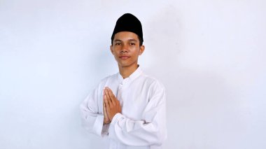 Genç Asyalı müslüman gülümseyen yüz ifadesi izole edilmiş beyaz arkaplan ile selamlama hareketi. İslam ayını selamlıyoruz.