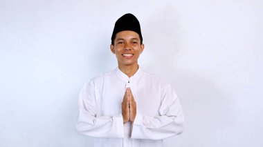 Genç Asyalı müslüman gülümseyen yüz ifadesi izole edilmiş beyaz arkaplan ile selamlama hareketi. İslam ayını selamlıyoruz.