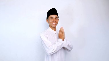 Genç Asyalı müslüman gülümseyen yüz ifadesi izole edilmiş beyaz arkaplan ile selamlama hareketi. İslam ayını selamlıyoruz.