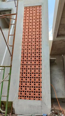 installation of perforated motif roster with brick red color on the wall. serves for air ventilation and looks beautiful facade.