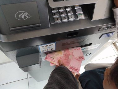 withdraw cash at an ATM machine. Bali - Indonesia ; January 1, 2023.