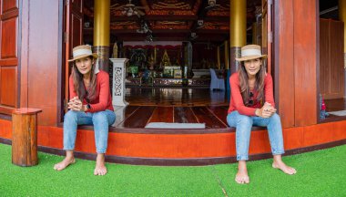 Pamorama of twin Asian women with old building background at Phayao province, Thailand.