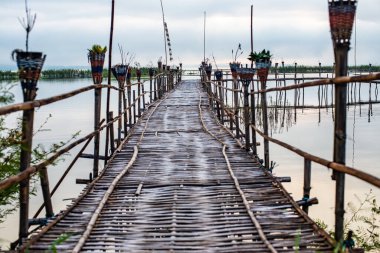Small wooden bridge with Kwan Phayao lake at sunrise, Thailand.