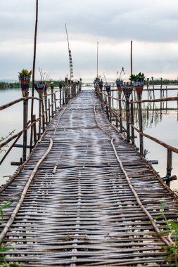 Small wooden bridge with Kwan Phayao lake at sunrise, Thailand.
