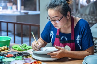 LAMPANG, THAILAND - March 6, 2020 : A woman painting on white ceramic plate, Lampang Province.