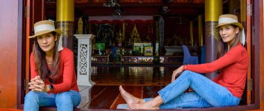 Pamorama of twin Asian women with old building background at Phayao province, Thailand.