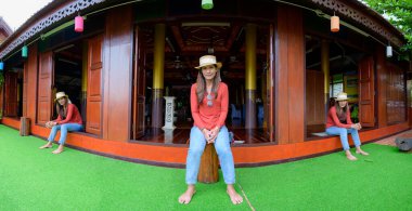 Pamorama of triple Asian female tourists with old wooden building background at Phayao province, Thailand.
