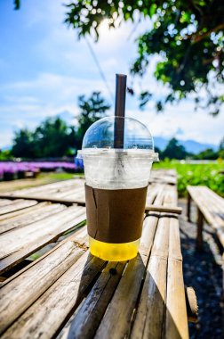 Fresh ice tea in plastic glass with flower garden, Chiang Mai province.