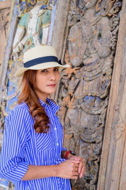 Thai Girl in Blue Dress with Ancient Wood Carving Background, Nan Province.