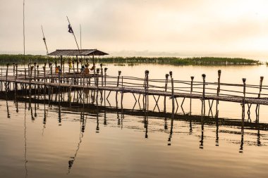 Small wooden bridge with Kwan Phayao lake at sunrise, Thailand.