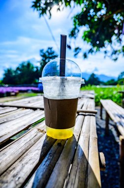 Fresh ice tea in plastic glass with flower garden, Chiang Mai province.