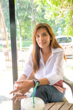 Asian woman in white shirt sitting in a coffee shop at Chiang Mai Province.