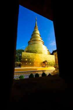 Ancient golden pagoda in window frame at Wat Phra Singh temple, Chiang Mai province.