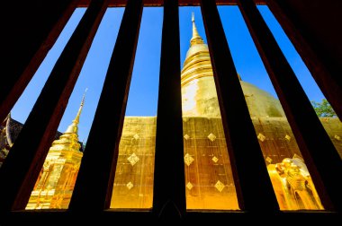 Ancient golden pagoda in window frame at Wat Phra Singh temple, Chiang Mai province.