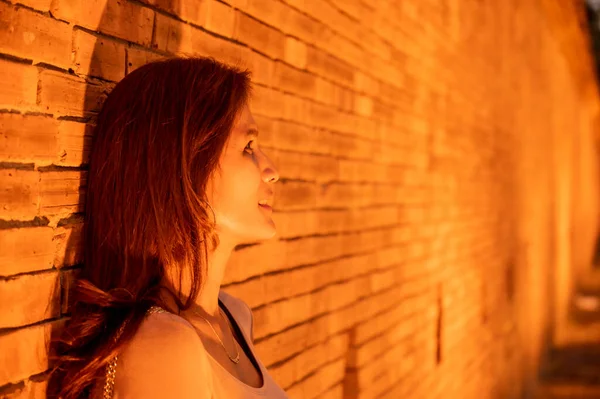 stock image Thai woman with old brick wall in the evening, Chiang Mai.