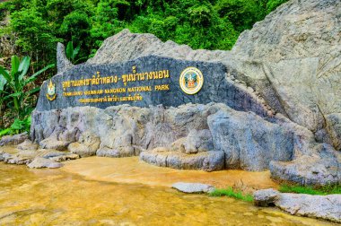 CHIANG RAI, THAILAND - July 18, 2020 : Thamluang Khunnam Nangnon National Park entrance sign with stone surrounding and trees, Thailand.