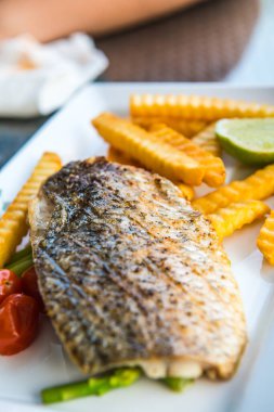 Tayland 'da, beyaz tabakta kızarmış patates kızartması ve ızgara tuzlu levrek..